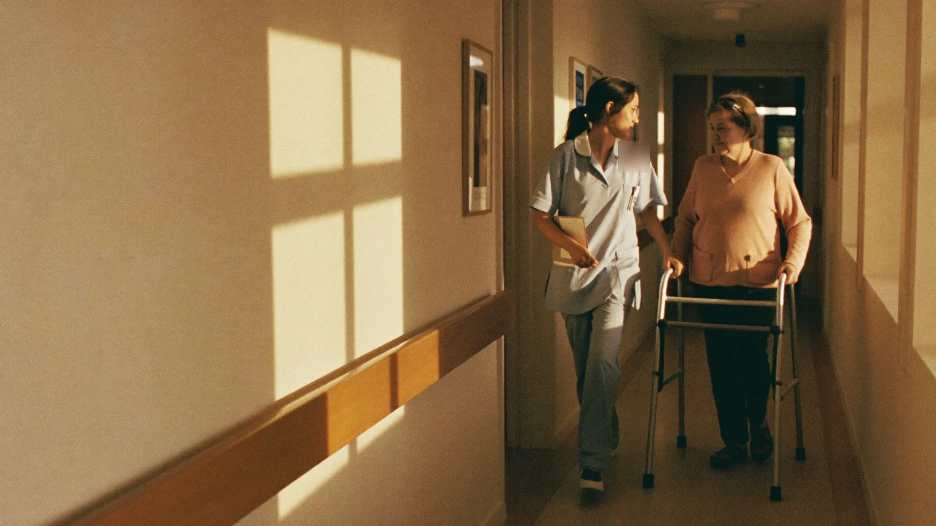 A nurse walking with a resident along a sunlit corridor at Beaver County Memorial Hospital